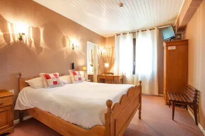 a bedroom with a large bed and a window at Logis Hôtel et Restaurant La Bombardière in Cuq-Toulza