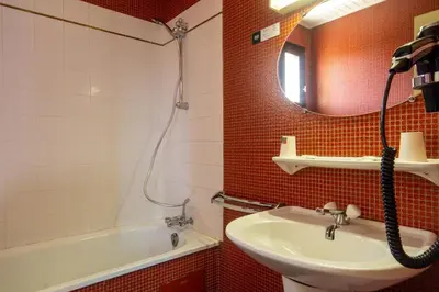 a bathroom with a sink and a tub and a mirror at Logis Hôtel et Restaurant La Bombardière in Cuq-Toulza