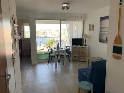 a living room with a table and chairs and a window at Cap Gruissan Vacances (11) in Gruissan