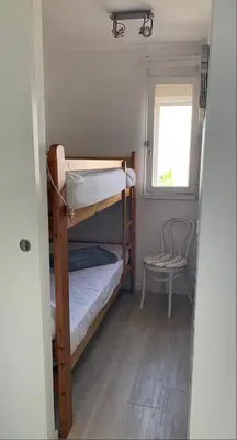 a small room with two bunk beds and a chair at Cap Gruissan Vacances (11) in Gruissan