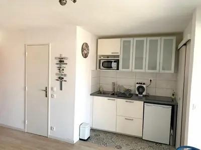 a kitchen with white cabinets and a microwave at Cap Gruissan Vacances (11) in Gruissan