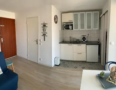 a kitchen with white cabinets and a blue couch at Cap Gruissan Vacances (11) in Gruissan