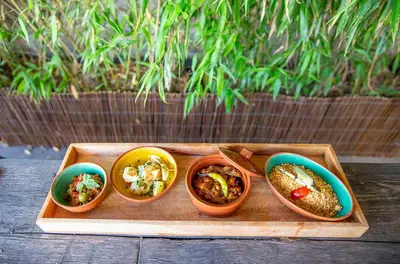 four small bowls of food on a wooden tray at Ecole Olargues - Chambres & restaurant - Teritoria in Olargues