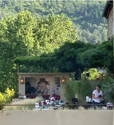 a woman sitting at a table in front of a restaurant at Ecole Olargues - Chambres & restaurant - Teritoria in Olargues