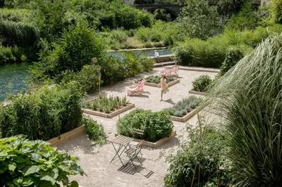 a woman walking through a garden with plants at Ecole Olargues - Chambres & restaurant - Teritoria in Olargues