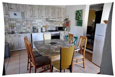 a kitchen with a table and chairs and a kitchen with white appliances at Le Moulin du Christ in Peyrefitte-sur-lʼHers