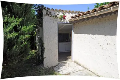 a white house with a door open to a yard at Le Moulin du Christ in Peyrefitte-sur-lʼHers