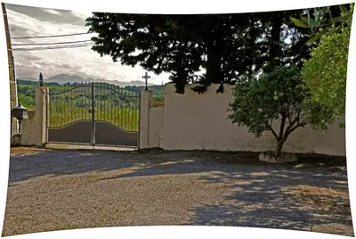 a fence with a gate with a tree in front at Le Moulin du Christ in Peyrefitte-sur-lʼHers