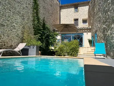 a swimming pool with two chairs and an umbrella at Chez Elia, pour les amoureux des vieilles pierres in Cesseras