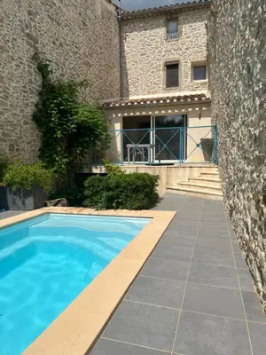 a house with a swimming pool in front of a building at Chez Elia, pour les amoureux des vieilles pierres in Cesseras