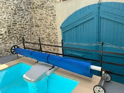 a pool with a blue water slide next to a building at Chez Elia, pour les amoureux des vieilles pierres in Cesseras