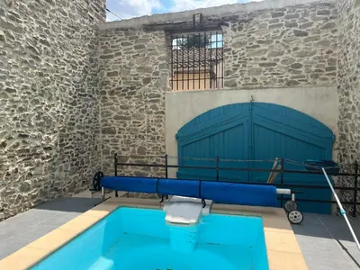 a building with a swimming pool and a building with a gate at Chez Elia, pour les amoureux des vieilles pierres in Cesseras