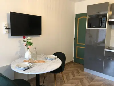 a small table in a kitchen with a tv on the wall at Les Palmiers de Gruissan, T2, Vue Port ! in Gruissan
