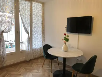 a room with a table and chairs and a television at Les Palmiers de Gruissan, T2, Vue Port ! in Gruissan
