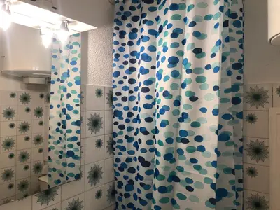 a bathroom with a blue and white shower curtain at Les Palmiers de Gruissan, T2, Vue Port ! in Gruissan