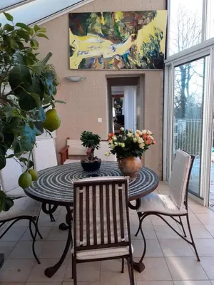 a dining room table with chairs and a painting on the wall at La Bergerie in Lagarrigue