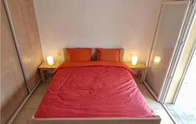 a red bed in a small room with two lamps at 3 Bedroom Nice Home In Quarante in Quarante