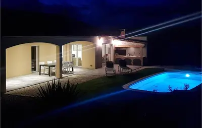 a swimming pool at night with a table and chairs at 3 Bedroom Nice Home In Quarante in Quarante