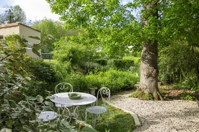 a dining room with a table and a stone wall at La Bastide des Roses in La Bastide-sur-lʼHers