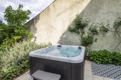 a bath tub sitting next to a wall at La Bastide des Roses in La Bastide-sur-lʼHers