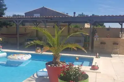 a pool with a palm tree next to a swimming pool at Gîte indépendant in Caux-et-Sauzens