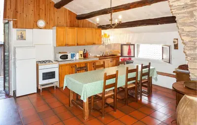 a kitchen with a table and chairs and a refrigerator at 2 Bedroom Amazing Home In Olargues in Olargues
