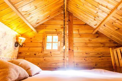 a bedroom with a bed in a wooden house at Les Cabanes d'Hestia in La Salvetat