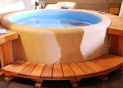a jacuzzi tub with a bench around it at Les Cabanes d'Hestia in La Salvetat