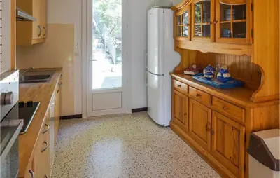 a kitchen with wooden cabinets and a white refrigerator at Awesome Home In Pierrerue in Pierrerue