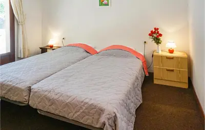 a bedroom with a bed and a table with a vase of flowers at Awesome Home In Pierrerue in Pierrerue