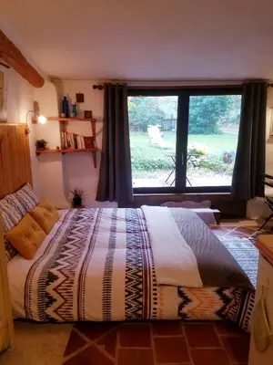 a bedroom with a large bed with a large window at Petit Gîte TARA avec SPA - Ariege Pyrénées in Péreille