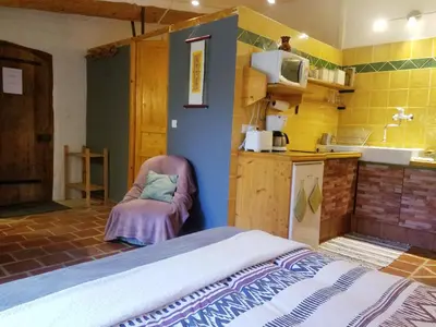 a room with a bed and a kitchen with yellow tiles at Petit Gîte TARA avec SPA - Ariege Pyrénées in Péreille
