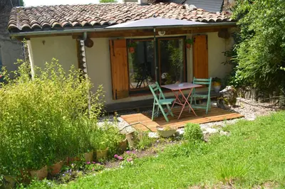 a small house with a table and chairs on a deck at Petit Gîte TARA avec SPA - Ariege Pyrénées in Péreille