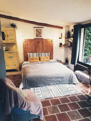 a bedroom with a bed and a brick floor at Petit Gîte TARA avec SPA - Ariege Pyrénées in Péreille