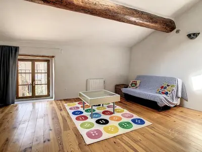 a room with a bed and a rug on the floor at La maison aux volets bleus in Caunes-Minervois