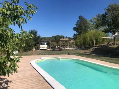 a swimming pool on a wooden deck next to a house at Domaine du Cammazet in Lapenne