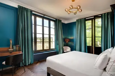 a bedroom with blue walls and a bed and windows at Domaine de la JASSO, Demeure de grand luxe au pied de la Cité de Carcassonne, piscines et parc animalier in Carcassonne
