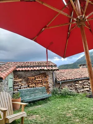a red umbrella in front of a building with a bench at la maison sous le château in Montségur