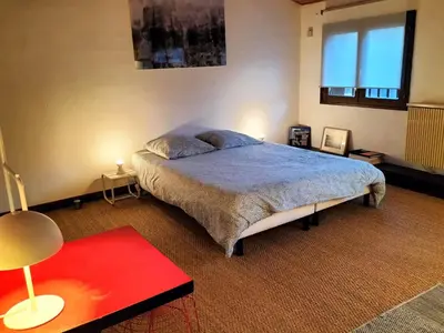 a bedroom with a bed and a red table at la maison sous le château in Montségur