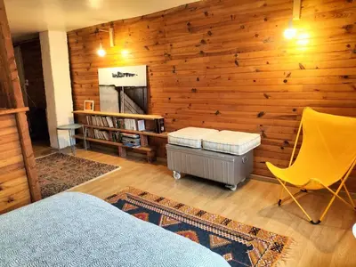 a bedroom with a wooden wall with a bed and a chair at la maison sous le château in Montségur