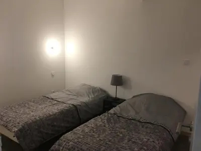 a bedroom with two beds and a lamp on the wall at La Cathare Appartement 2 chambres in Lézignan-Corbières