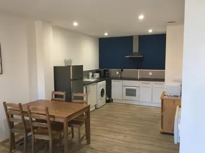a kitchen with a table and chairs and a refrigerator at La Cathare Appartement 2 chambres in Lézignan-Corbières