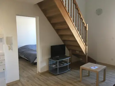 a bedroom with a bed and a staircase with a television at La Cathare Appartement 2 chambres in Lézignan-Corbières