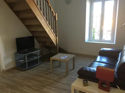 a living room with a couch and a tv and a staircase at La Cathare Appartement 2 chambres in Lézignan-Corbières