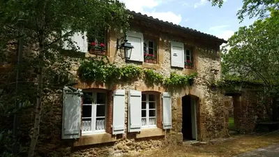 an old stone house with white windows and plants at Domaine de Las Planques in Vaudreuille