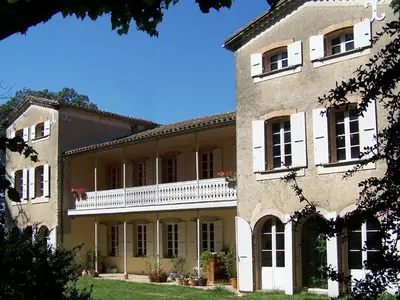a large stone building with white windows and balconies at Domaine de Las Planques in Vaudreuille