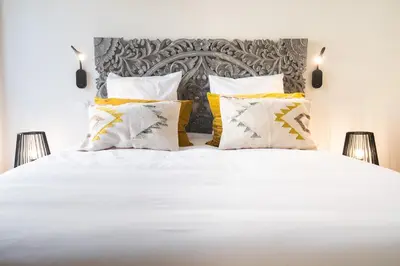 a bedroom with a white bed with yellow pillows at Le Jardin de La Tour Pinte in Carcassonne