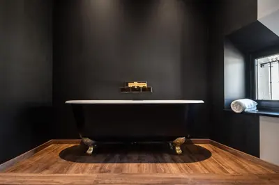 a bath tub in a black bathroom with a wooden floor at Le Loft de La Tour Pinte in Carcassonne