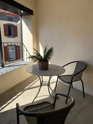 a table and two chairs with a plant on a balcony at Au pied de la Cité Médiévale, piscine, vue extraordinaire, gîte La Trivala à Carcassonne in Carcassonne