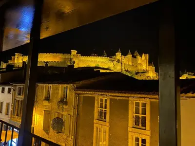 a view of a castle at night from a window at Au pied de la Cité Médiévale, piscine, vue extraordinaire, gîte La Trivala à Carcassonne in Carcassonne